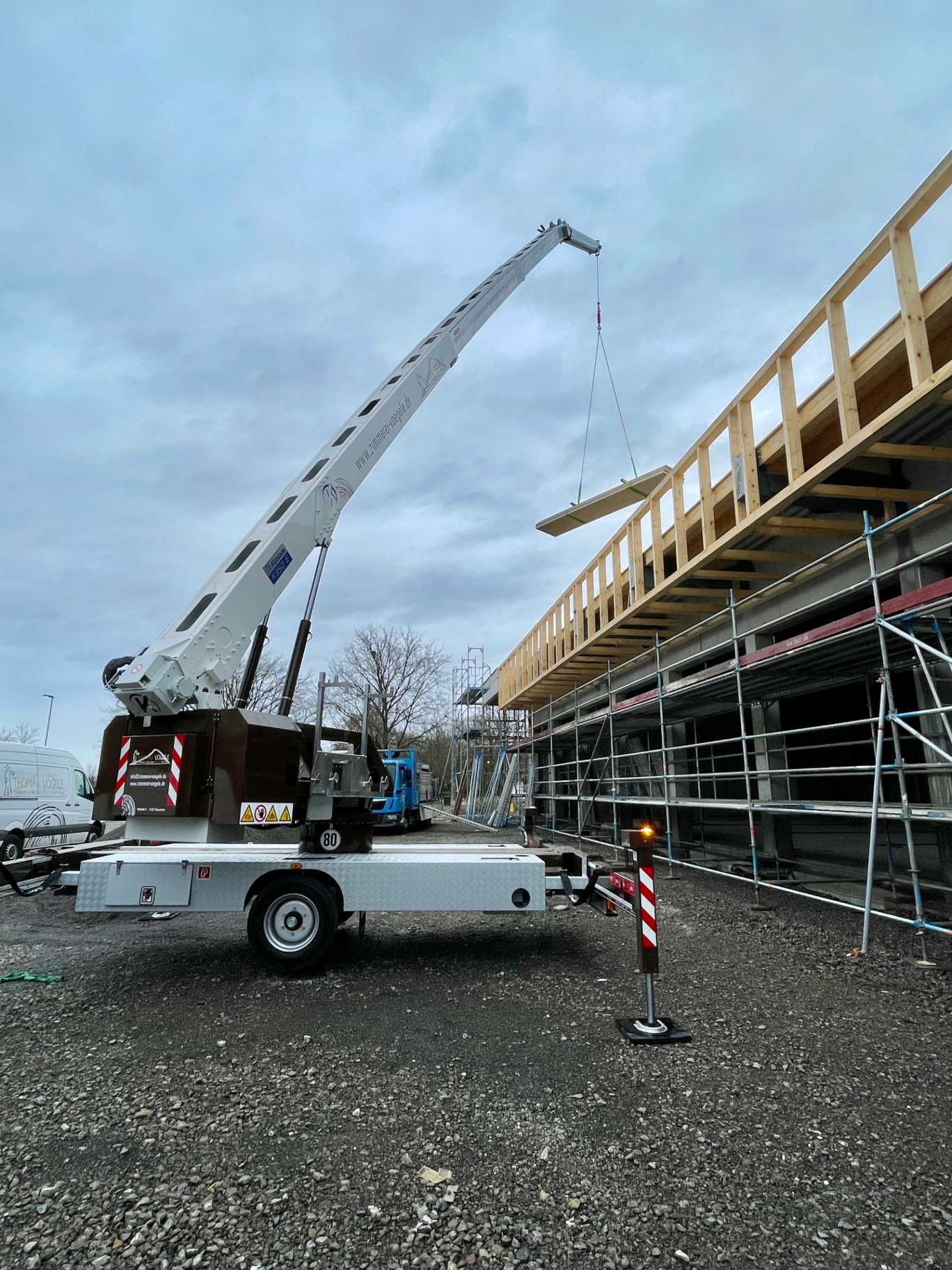 Kranarbeit auf der Baustelle — Holzbalken schweben ein